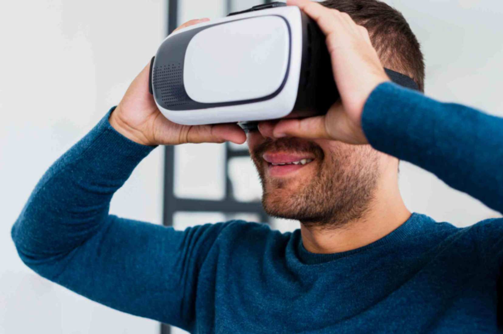 A man wearing a VR headset and is smiling. He is also wearing a blue shirt